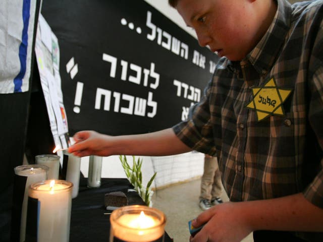 A schoolboy, wearing a yellow star of David, lights memorial candles during a Holocaust Memorial Day ceremony on 16 April 2007 in Hod Hasharon, Israel