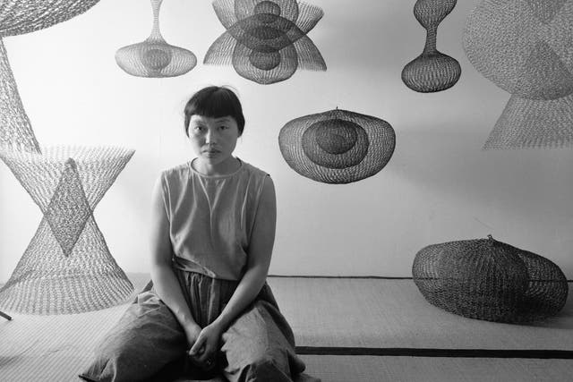 Japanese-American artist sculptor Ruth Asawa kneels on the floor amid several of her works, November 1954.