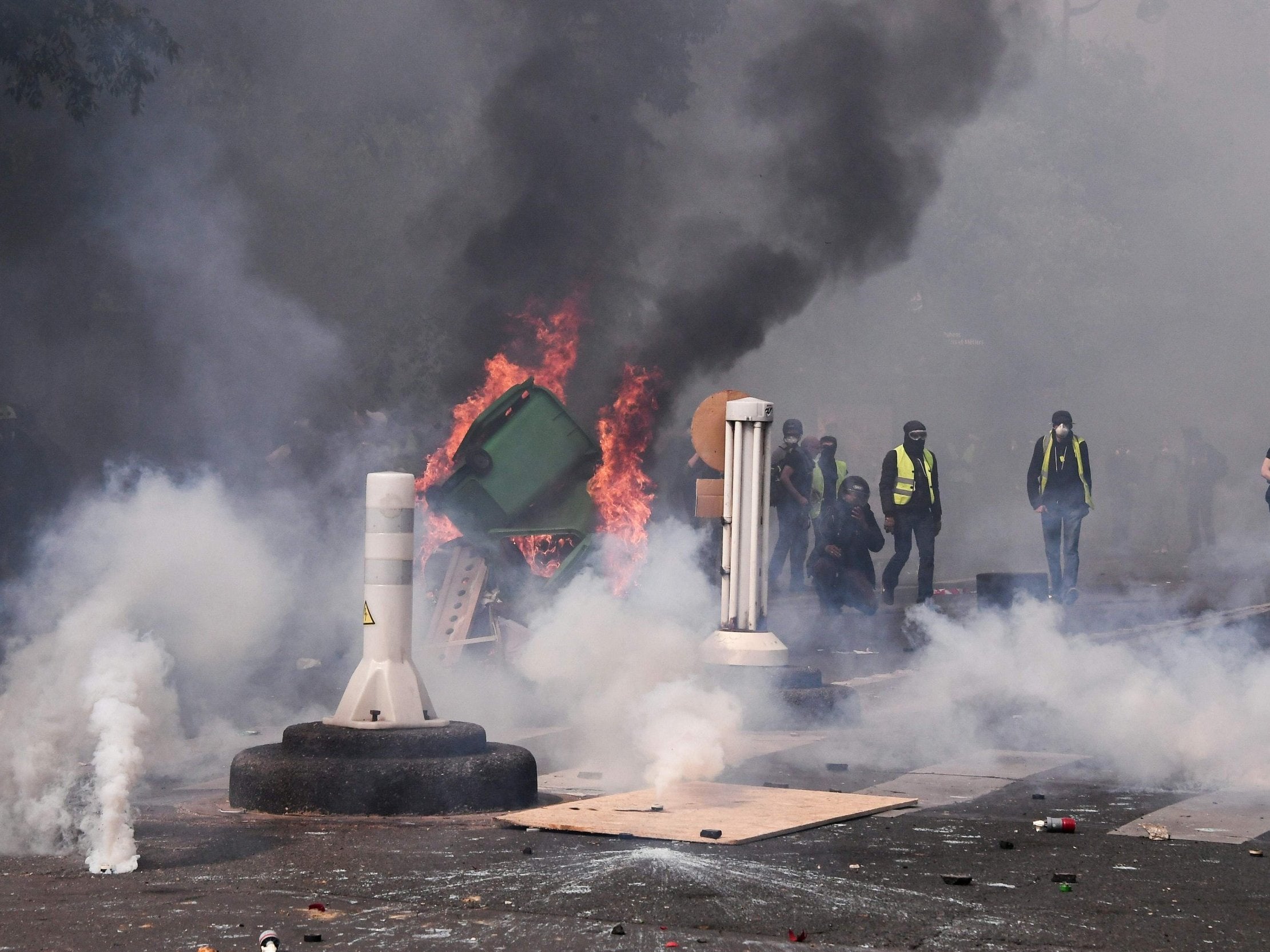 Protesters stand amid tear gas as they clash with police during a May Day demonstration in Paris