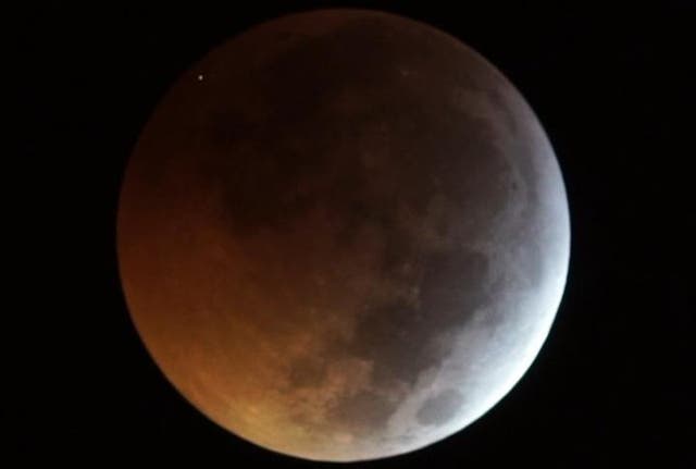 The flash from the impact of the meteorite on the eclipsed Moon, seen as the dot at top left