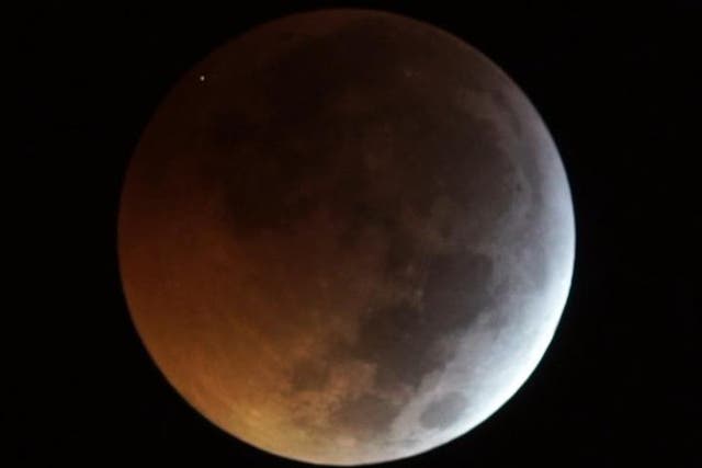 The flash from the impact of the meteorite on the eclipsed Moon, seen as the dot at top left