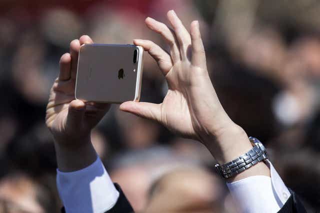 A guest attendee uses an iPhone to take a photograph of Japan's Prime Minister Shinzo Abe during the cherry blossom viewing party at the Shinjuku Gyoen National Garden on April 13, 2019 in Tokyo, Japan