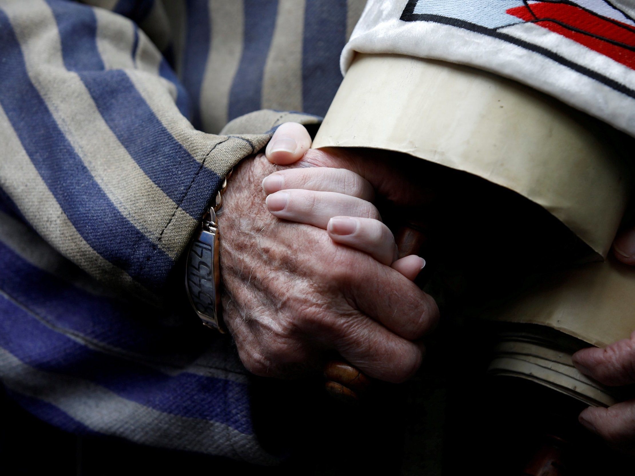 A Holocaust survivor holds his granddaughter’s hand as he arrives to take part in this year’s march in Poland