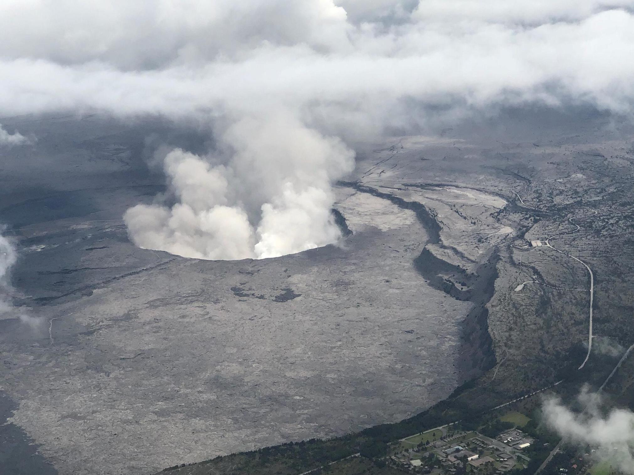 An aerial view of Kilauea volcano's summit caldera and an ash plume billowing from Halemaumau, a crater within the caldera