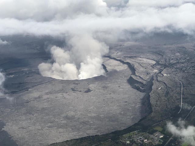 An aerial view of Kilauea volcano's summit caldera and an ash plume billowing from Halemaumau, a crater within the caldera