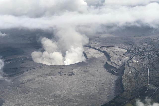 An aerial view of Kilauea volcano's summit caldera and an ash plume billowing from Halemaumau, a crater within the caldera
