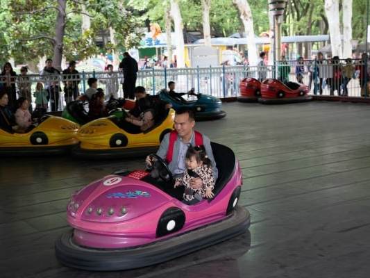 Zhang Yuewei and her father drive a bumper car in an amusement park in Wuhan (The Washington Post)