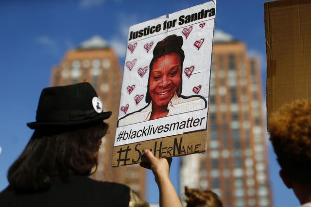 A woman holds a poster bearing the portrait of  Sandra Bland during a Michael Brown memorial rally in 2015 in New York.