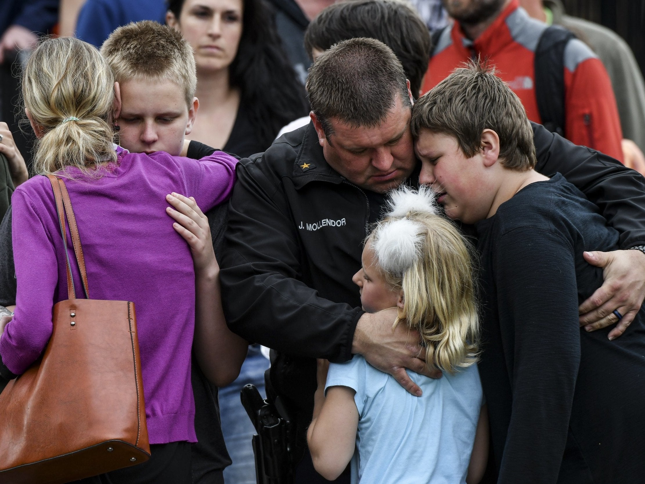 Parents comfort their children after being reunited at a recreation centre following the shooting