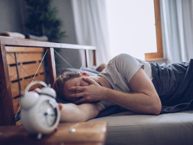 Sleeping man disturbed by alarm clock early in the morning