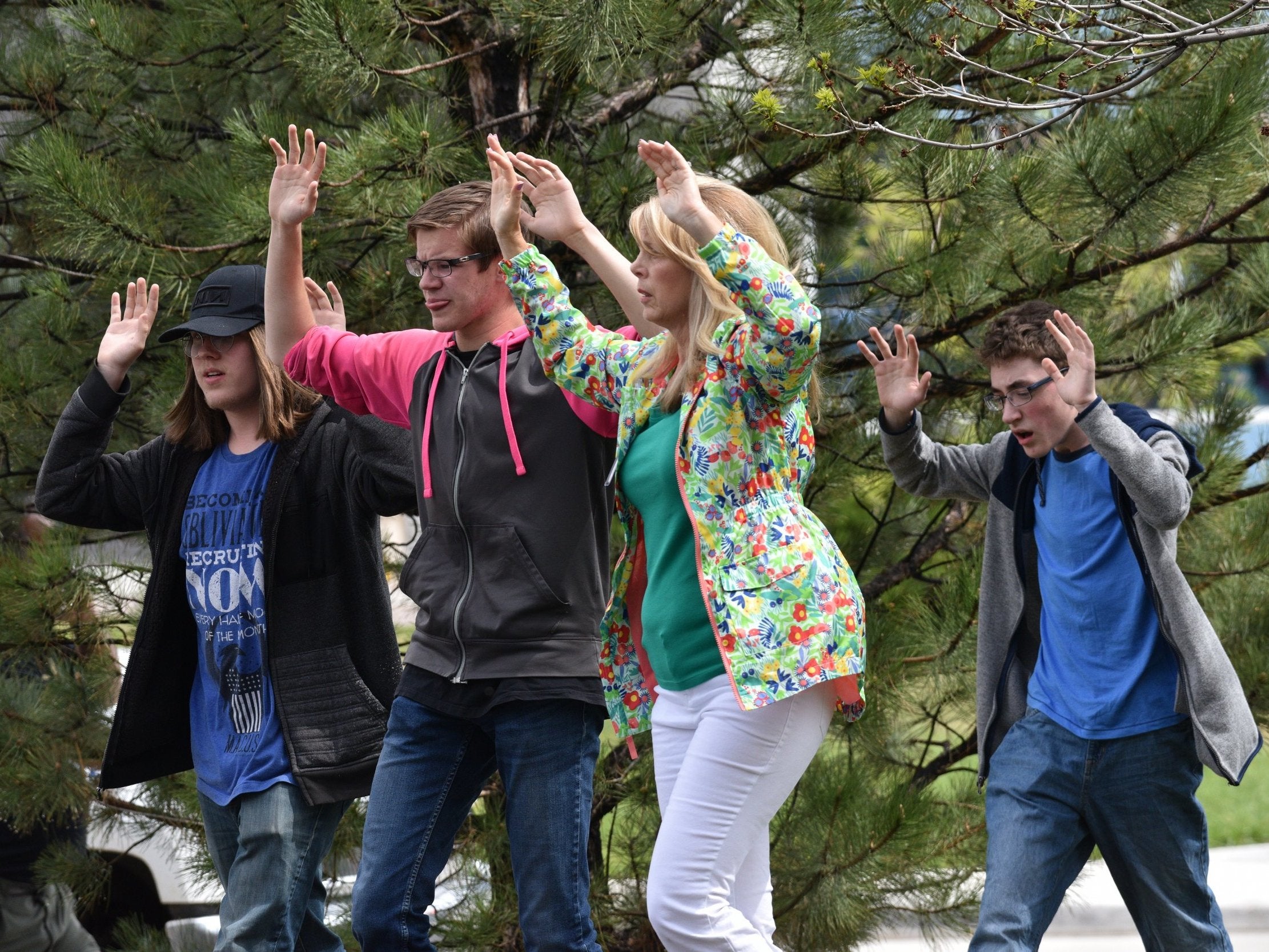 Students and teachers raise their arms as the leave the scene of the shooting at the Stem School Highlands Ranch