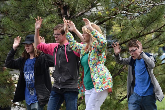 Students and teachers raise their arms as the leave the scene of the shooting at the Stem School Highlands Ranch