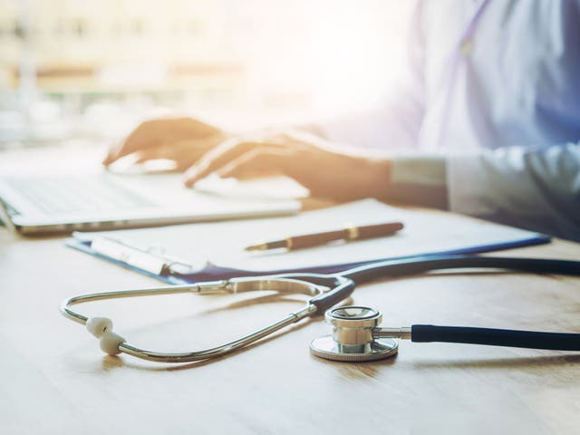 Doctor typing information on Laptop in Hospital office focus on Stethoscope