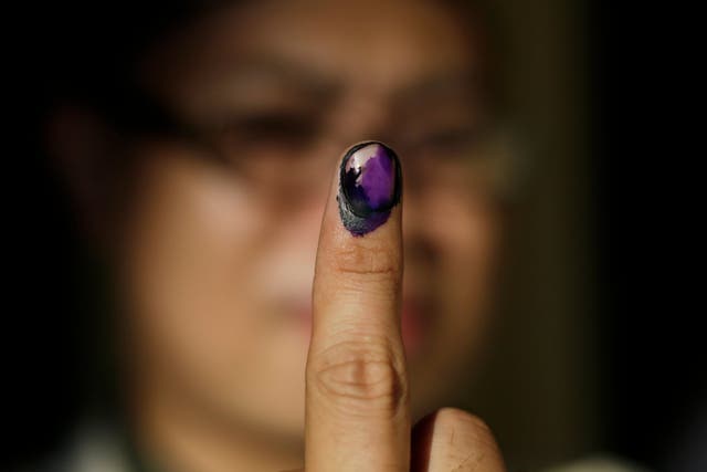 A Filipino displays her finger marked with indelible ink after voting at an elementary school turned into a voting precinct in Manila, Philippines, 13 May 2019.