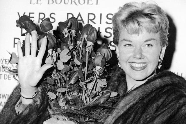 Doris Day is pictured in 1955 holding a bouquet of roses at Le Bourget Airport in Paris, France after flying in from London.