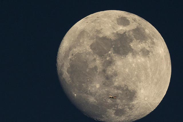 A plane flies past the Moon at sunset in London in 2015