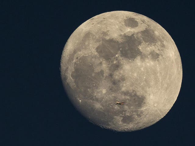A plane flies past the Moon at sunset in London in 2015