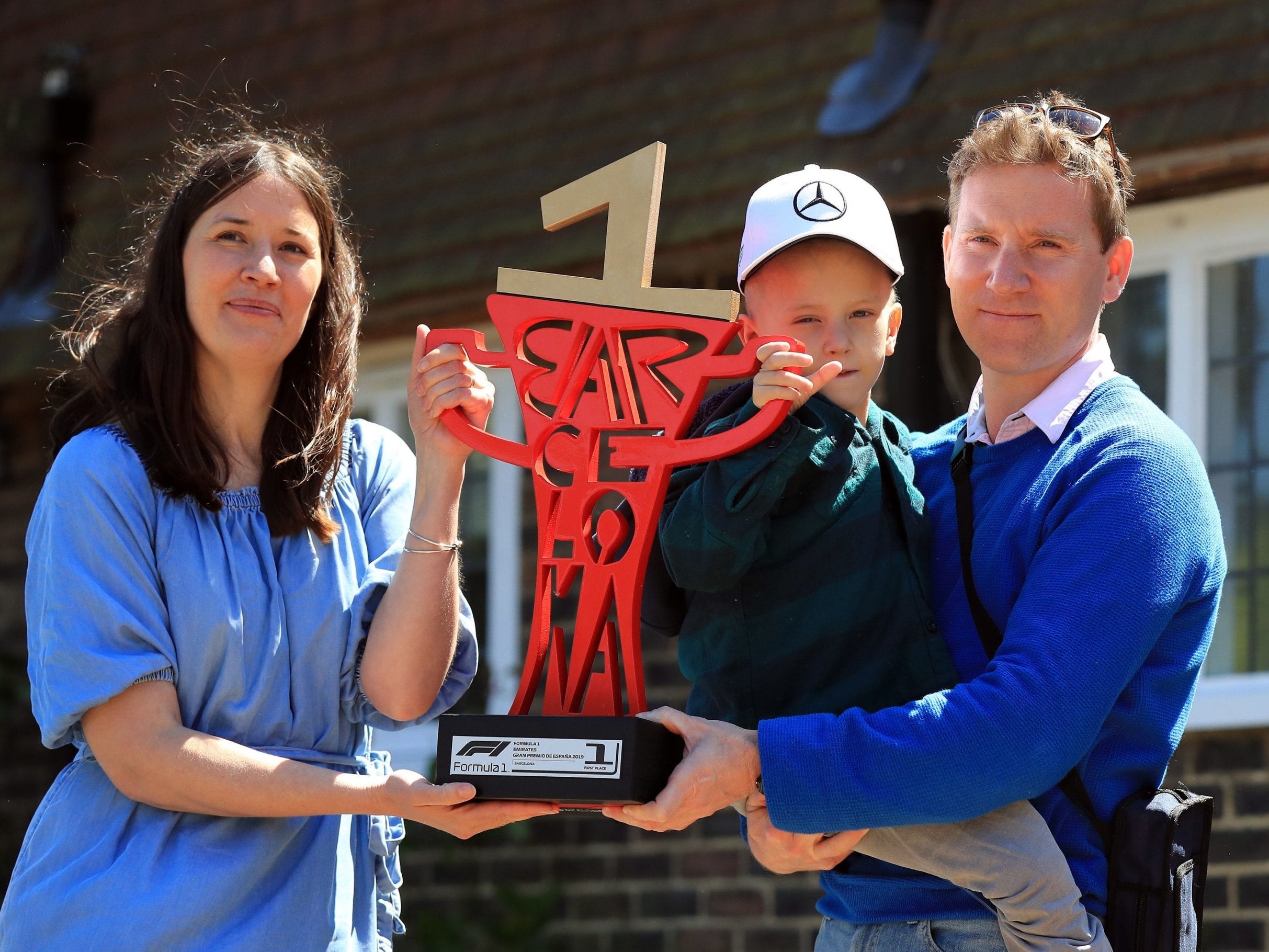 Five-year-old Harry Shaw with father James with mother Charlotte as they hold Lewis Hamilton's Spanish Grand Prix trophy