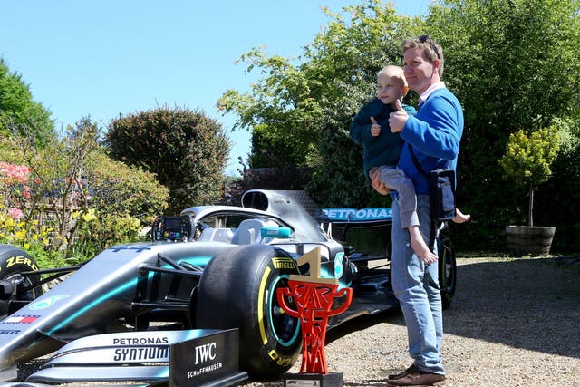 Five-year-old Harry Shaw is carried by his father James as they view one of Lewis Hamilton's Mercedes cars