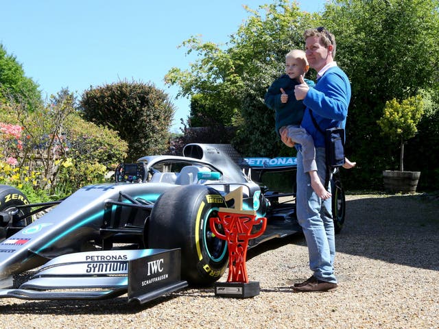 Five-year-old Harry Shaw is carried by his father James as they view one of Lewis Hamilton's Mercedes cars