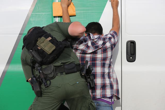 A US Border Patrol agent searches an immigrant from Central America while taking him into custody near Roma, Texas