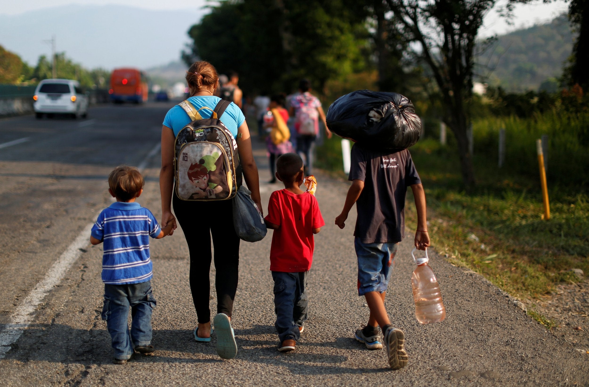 A migrant mother and her children walk along a road with other Central American migrants during their journey towards the US