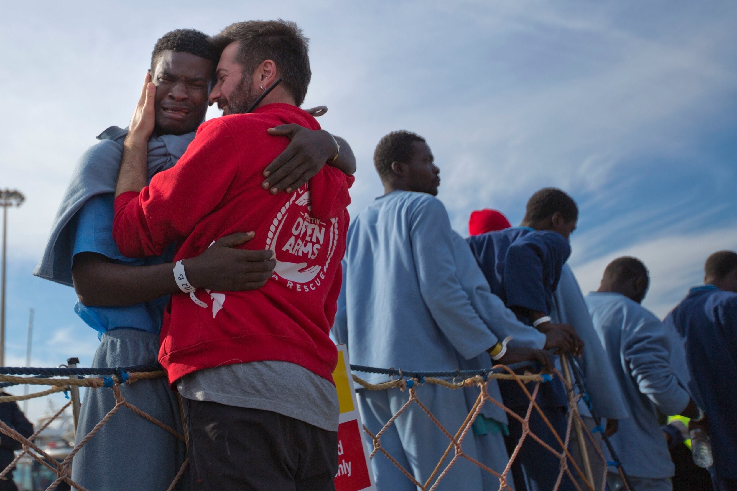 A young man cries with the head of Proactive Open Arms NGO as he leaves a rescue vessel in the Mediterranean Sea
