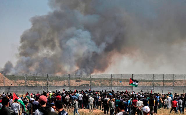 Palestinian protestors demonstrate by the border fence with Israel east of Gaza City as smoke billows from fields across the fence caused by inflammable material attached to balloons flown during the protest, on May 15, 2019