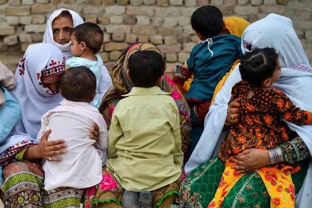 Pakistani women hold their HIV infected children as they gather at a house at Wasayo village in Rato Dero