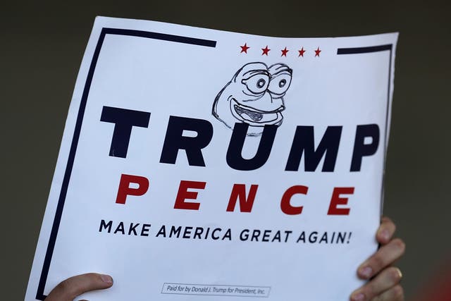 A supporter holds a campaign sign for Republican presidential nominee Donald Trump with 'Pepe the Frog' drawn on it during a rally in the Sun Country Airlines Hangar