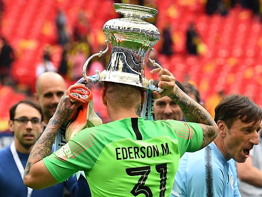 Ederson celebrates with the trophy