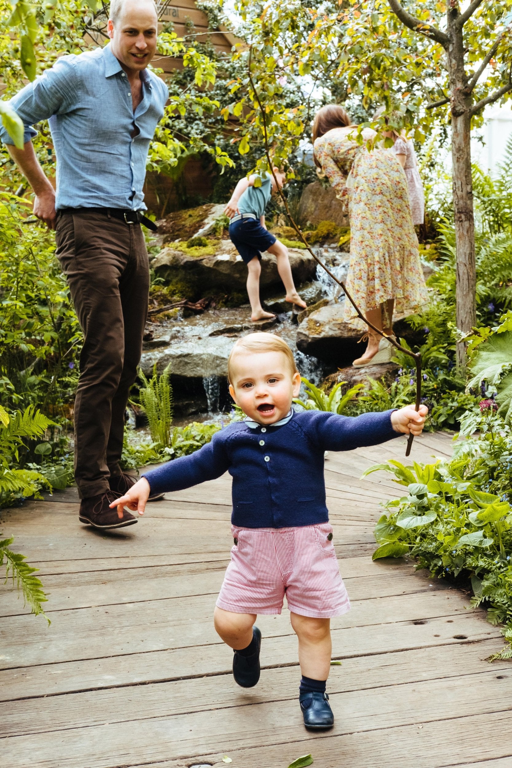 Prince William watches on as Prince Louis walks while holding a branch