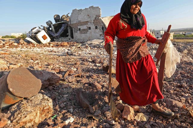 A woman salvages items from a building reportedly destroyed during airstrikes on the town of Kafranbel in the rebel-held part of the Syrian Idlib province, on 20 May 2019