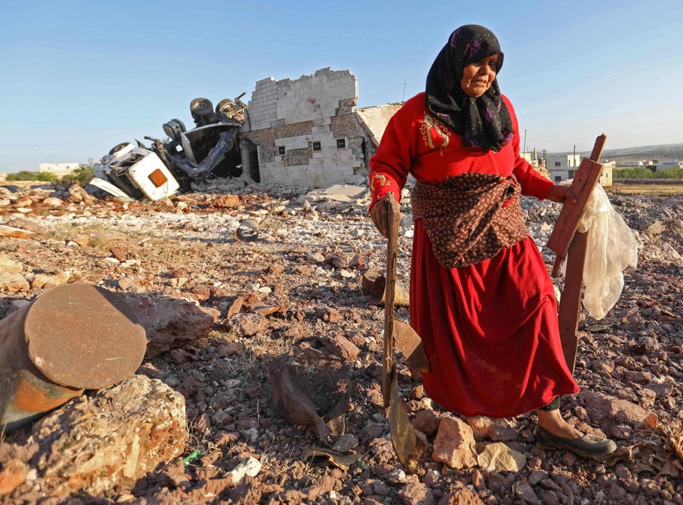 A woman salvages items from a building reportedly destroyed during airstrikes on the town of Kafranbel in the rebel-held part of the Syrian Idlib province, on 20 May 2019