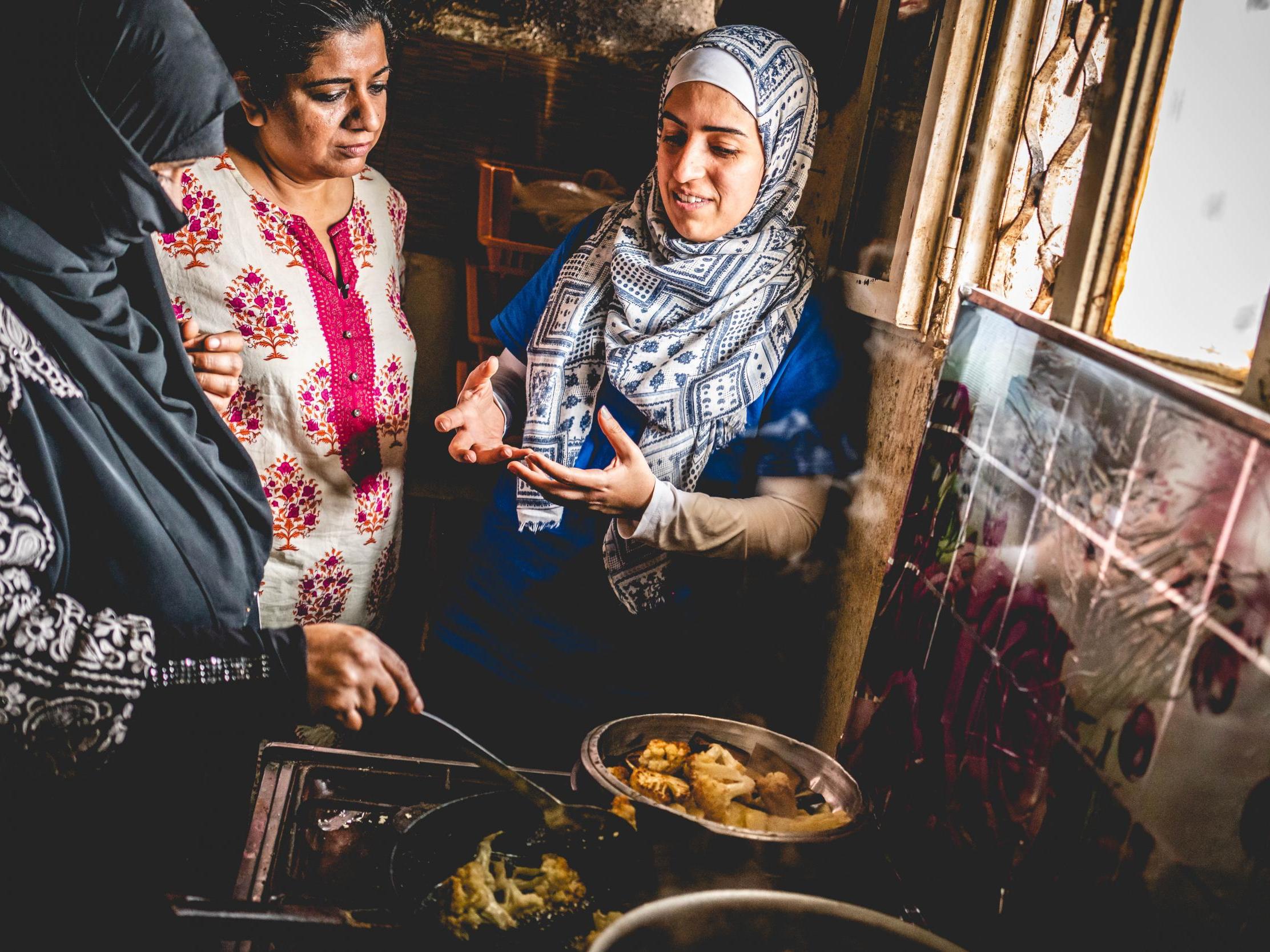 Asma Khan (middle) cooking with two refugees