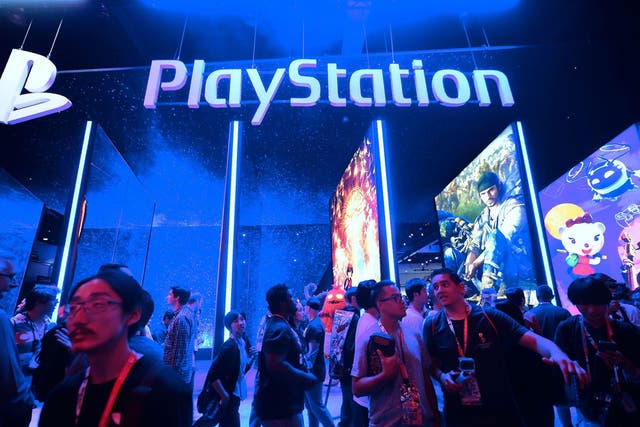 People wander in front of the Playstation posters at the 24th Electronic Expo, or E3 2018, in Los Angeles