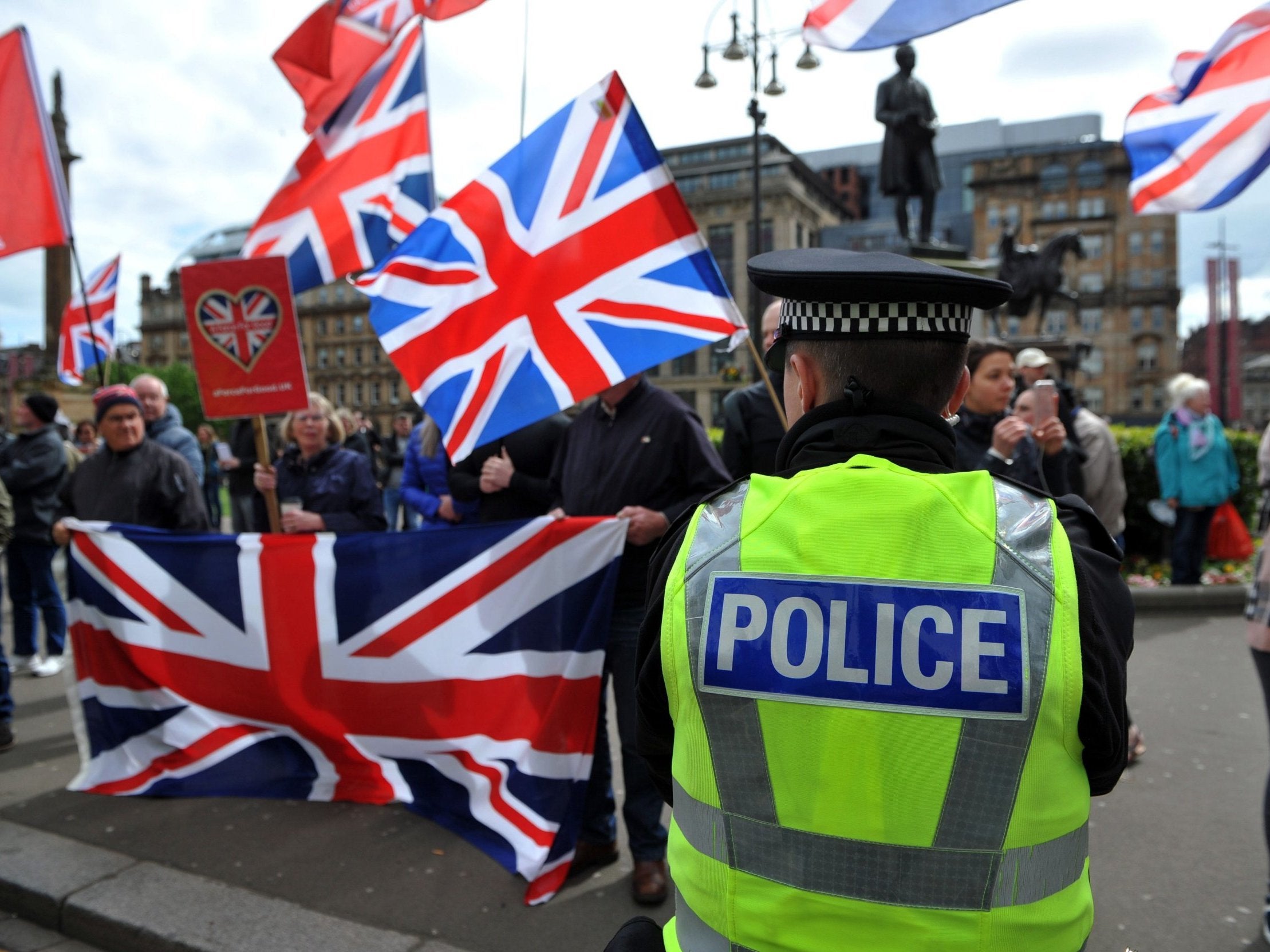 A police officer stands on duty near pro-Union demonstrators flying Union flags as they demonstrate against Pro-Scottish Independence activists marching through the streets of Glasgow during the All Under One Banner March for Independence on May 4, 2019