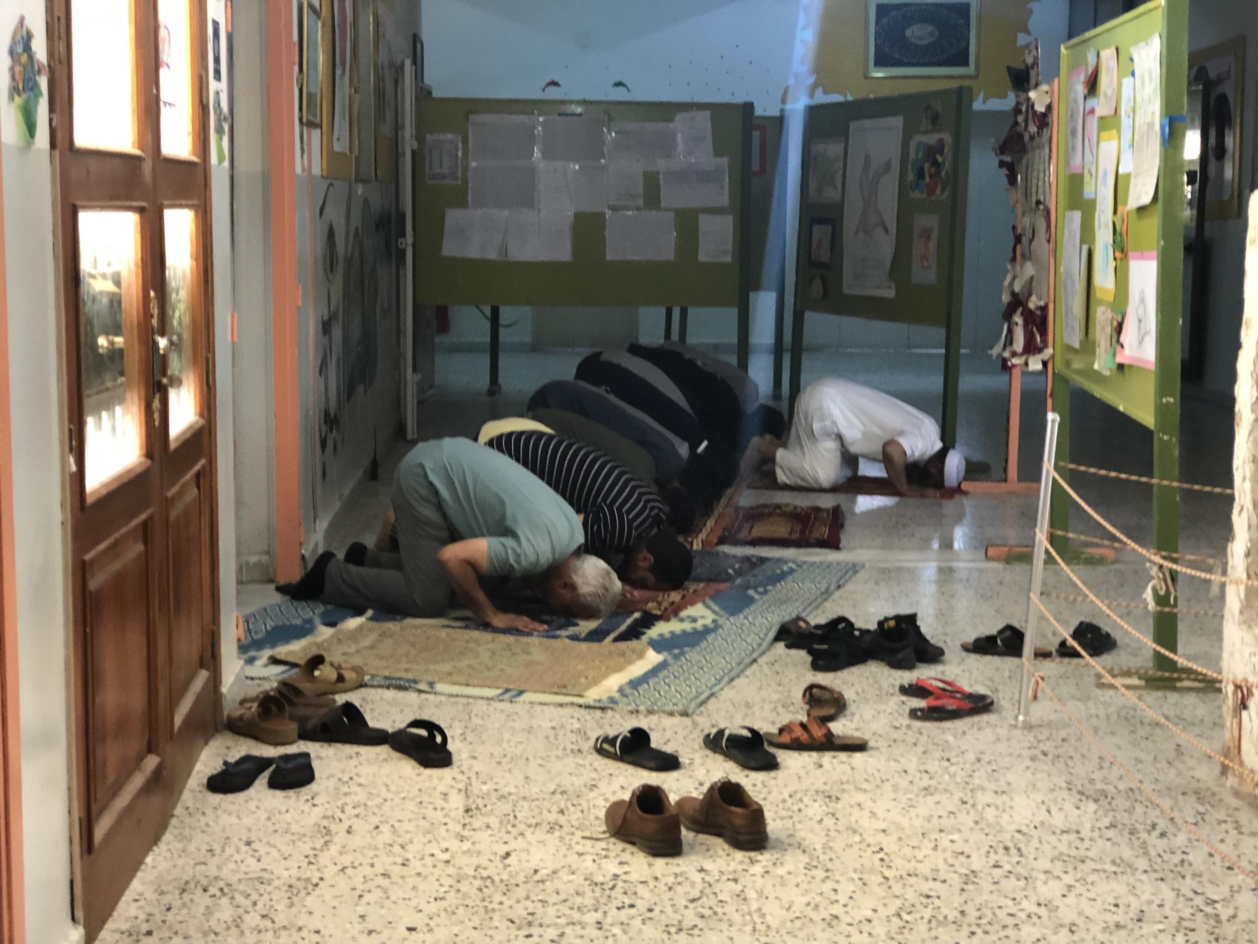 Men pray at a now shuttered school near central Tripoli, which is being used to house internally displaced people