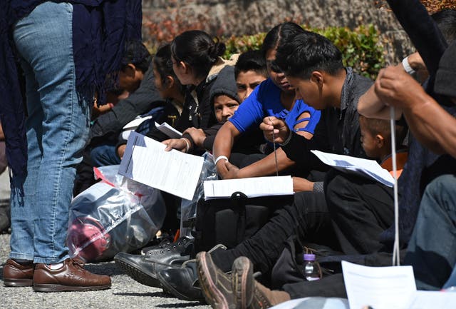 Asylum seekers sit outside the bus station after they were released from US border patrol vans, 22 May