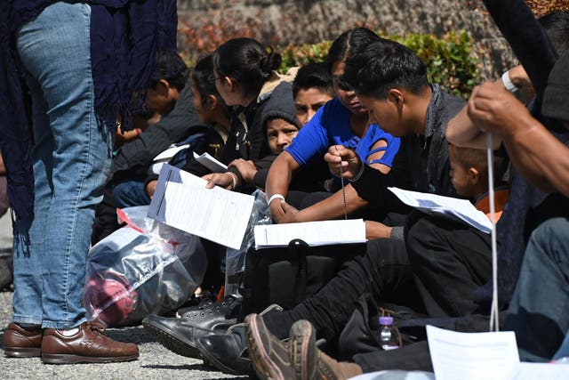 Asylum seekers sit outside the bus station after they were released from US border patrol vans, 22 May