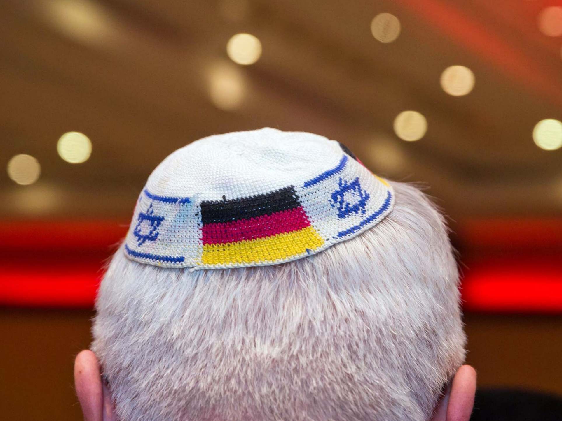 A man wears a Jewish skullcap with the flags of Germany and Israel