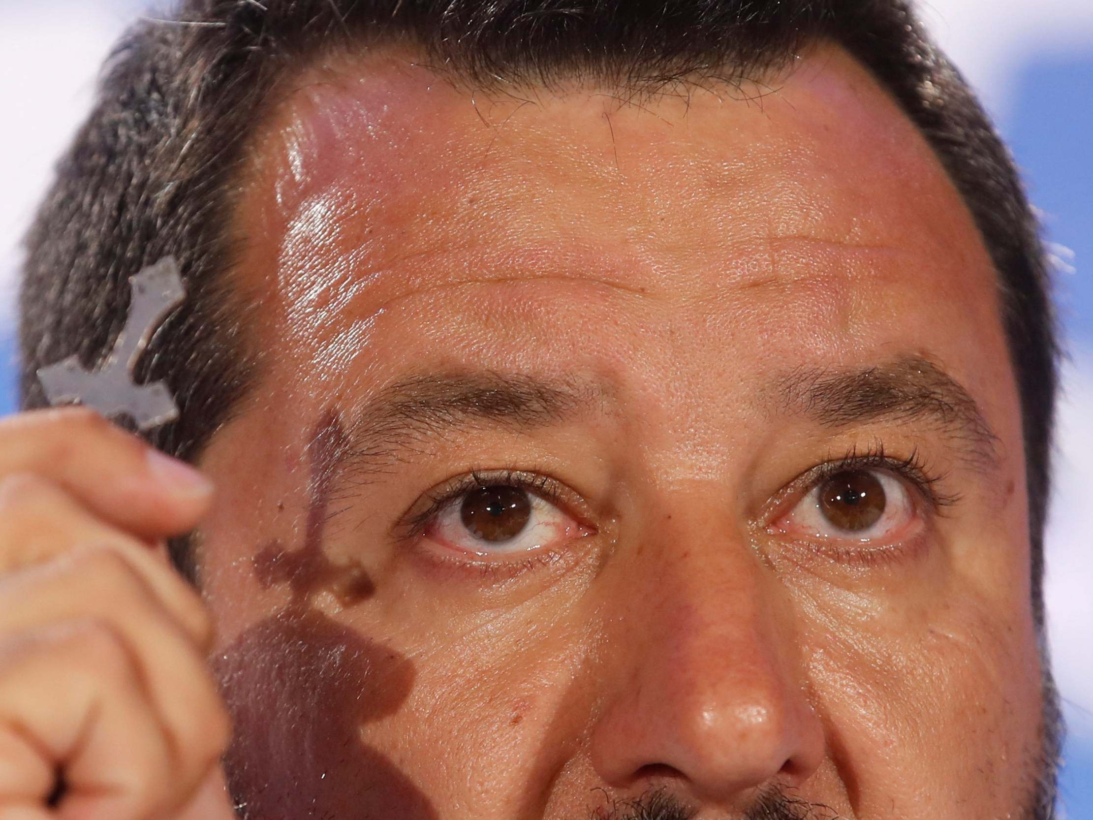 Matteo Salvini holds a crucifix as he talks to reporters during a press conference at the League headquarters in Milan on Monday