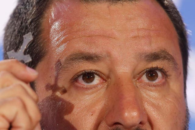 Matteo Salvini holds a crucifix as he talks to reporters during a press conference at the League headquarters in Milan on Monday