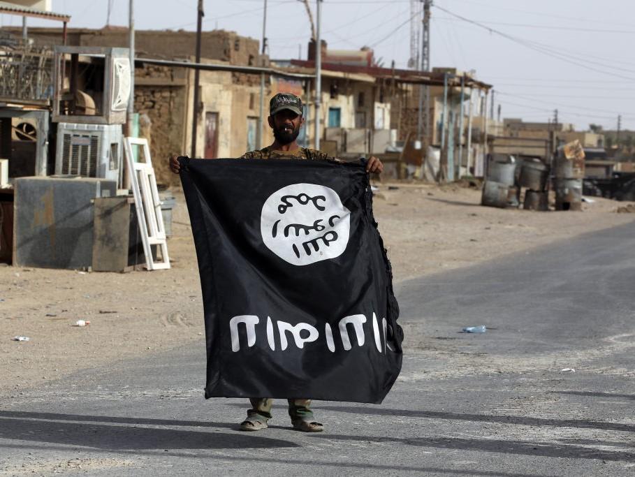 An Iraqi member of the Hashed al-Shaabi carries an upsidedown Islamic State (IS) group flag in the city of al-Qaim, Iraq on 3 November, 2017