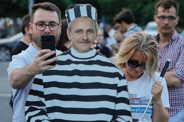 A man man takes a photo of himself next to at a cardboard depiction of Liviu Dragnea