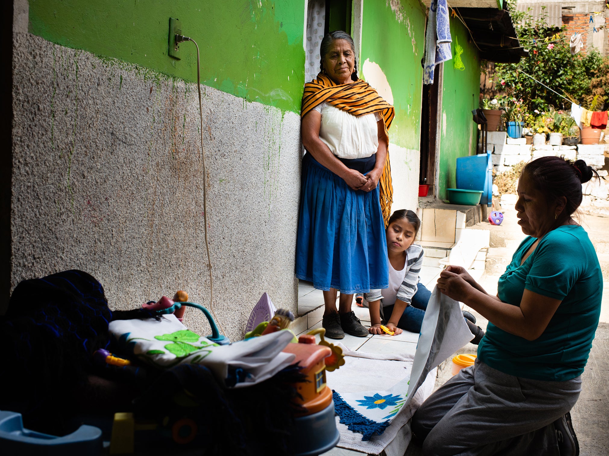 Romero Leon waits as her daughter Angelina Sánchez, 47, irons handmade pillowcases to take as gifts. Sánchez’s granddaughter Valeria Masias Fabian watches