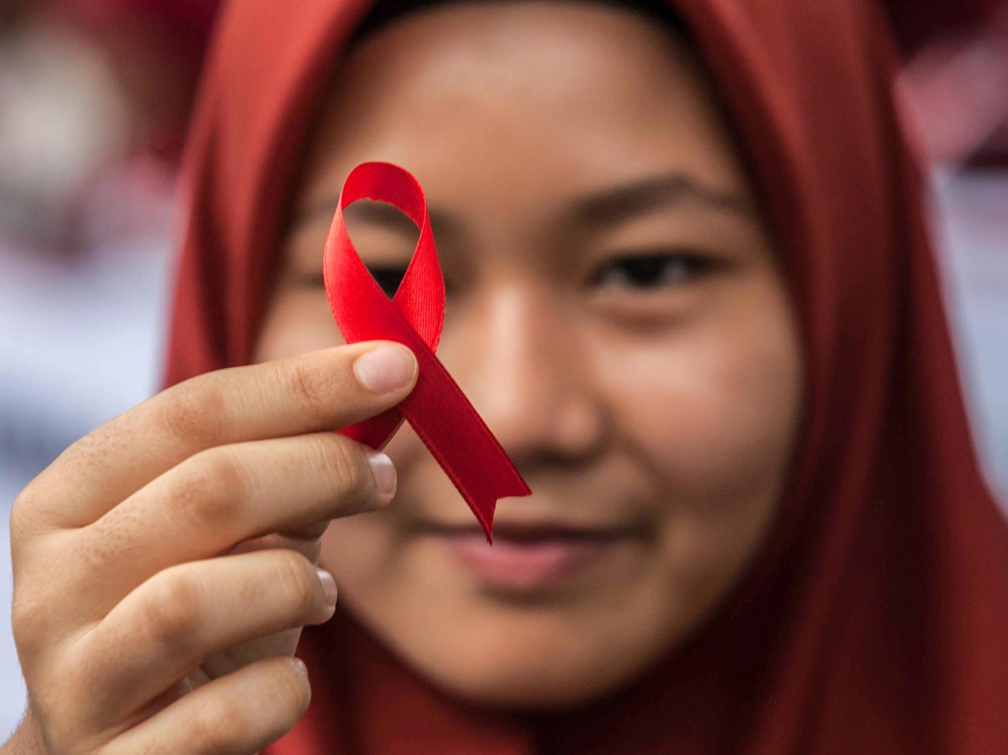 An Indonesian student holds a red ribbon as part of an HIV awareness event in Sumatra