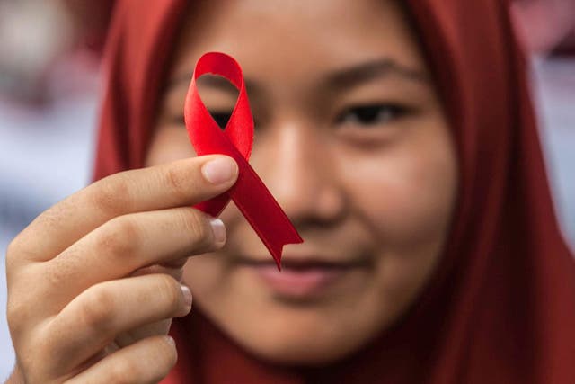 An Indonesian student holds a red ribbon as part of an HIV awareness event in Sumatra