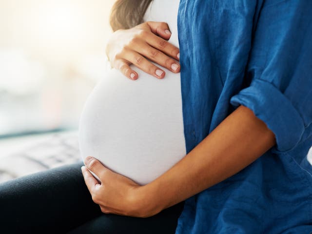 Pregnant woman holding her belly at home