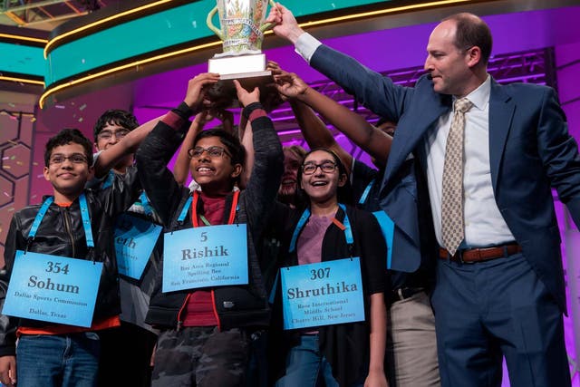 Scripps president and Chief Executive Officer Adam Symson (R) gives the trophy to the eight co-champions on the final day of the 2019 Scripps National Spelling Bee
